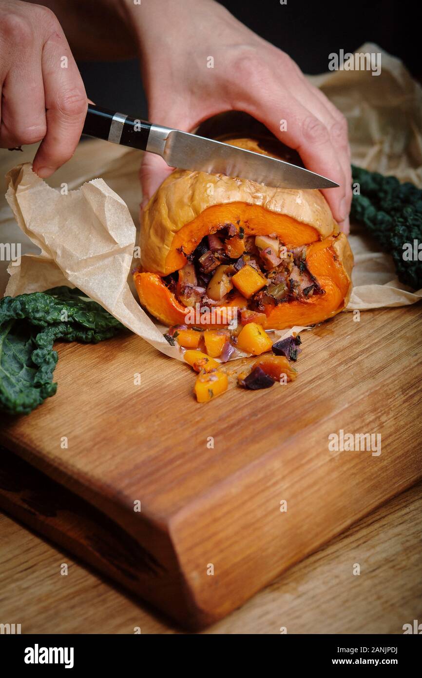 Zucca di Butternut ripiena arrosto con insalata di cavolo e ceci. Sano cibo vegano servito su un vassoio arancione con sfondo nero. Vista dall'alto / piatto Foto Stock