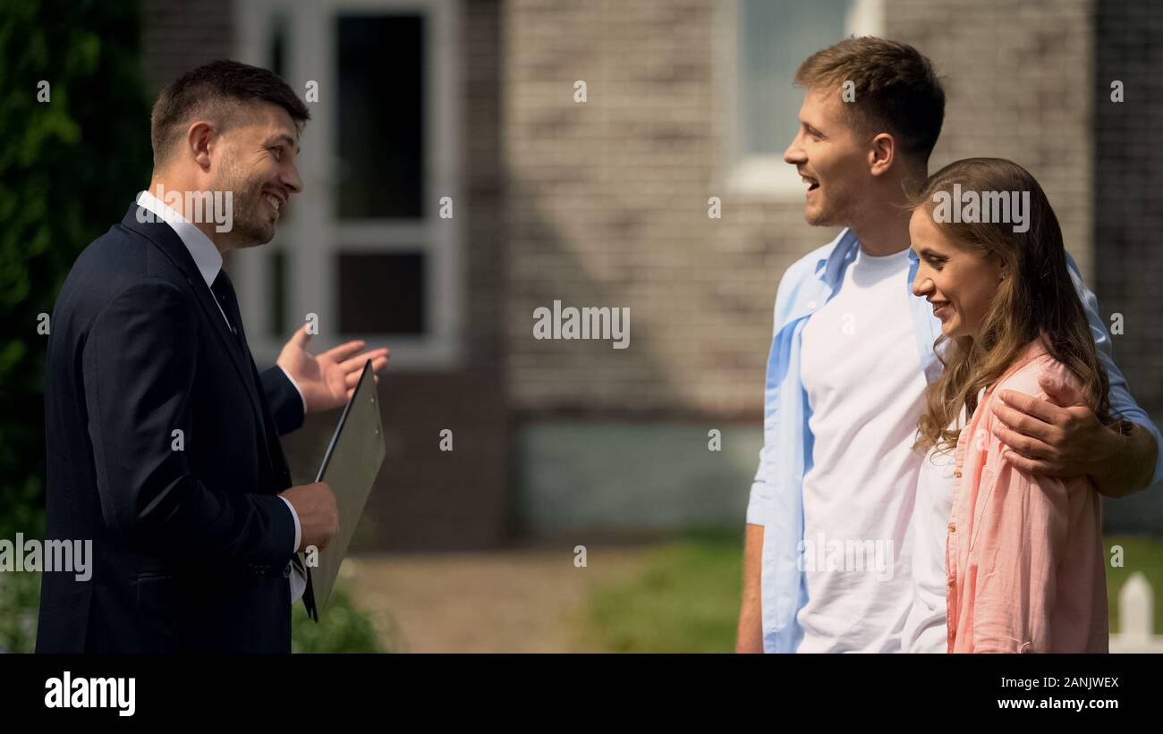 Gentile Agente immobiliare presentazione di cottage di lusso a famiglia giovane, pubblicità Foto Stock