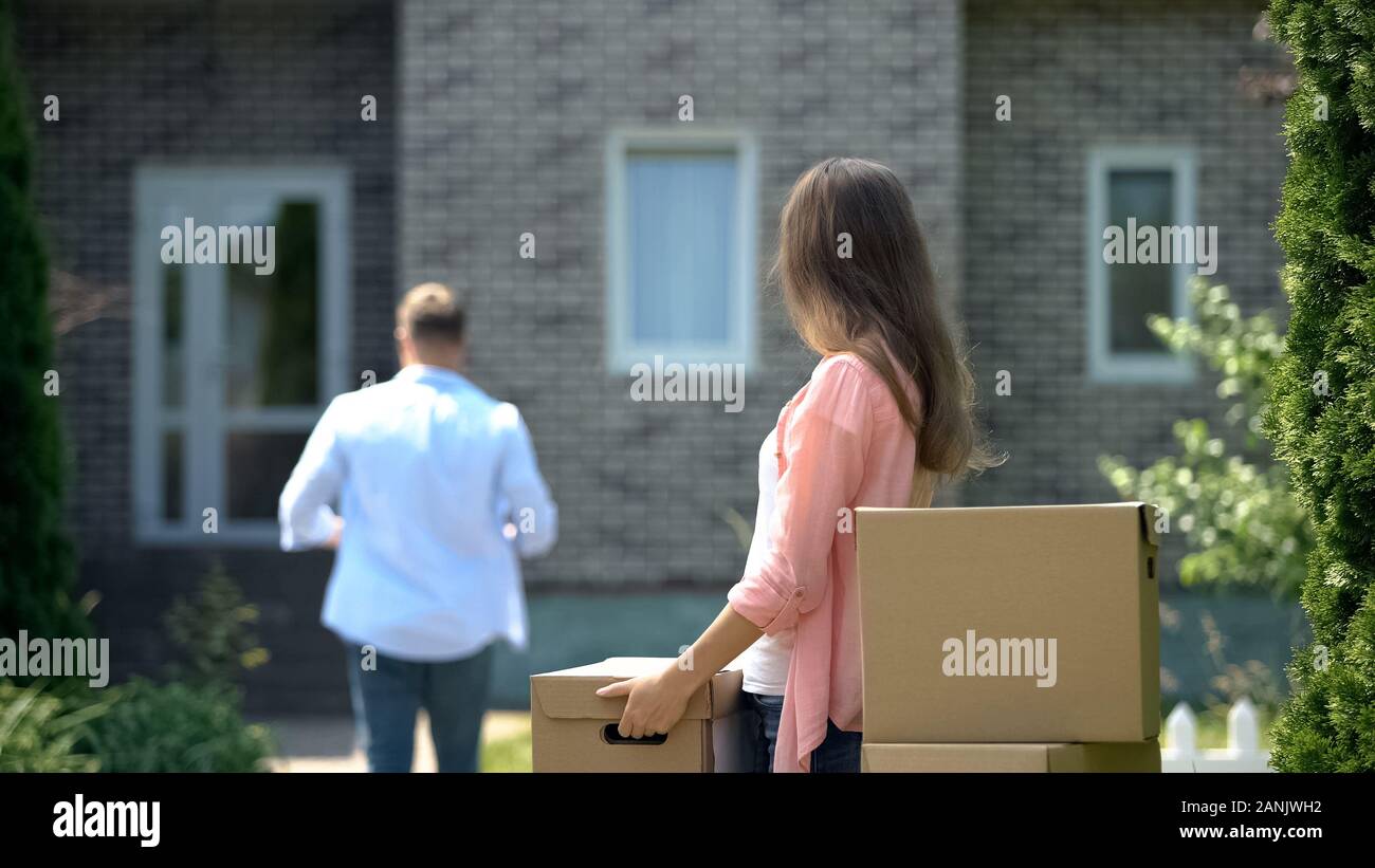 Famiglia di passare a casa nuova, marito portano pesanti scatole di cartone, affitto Foto Stock