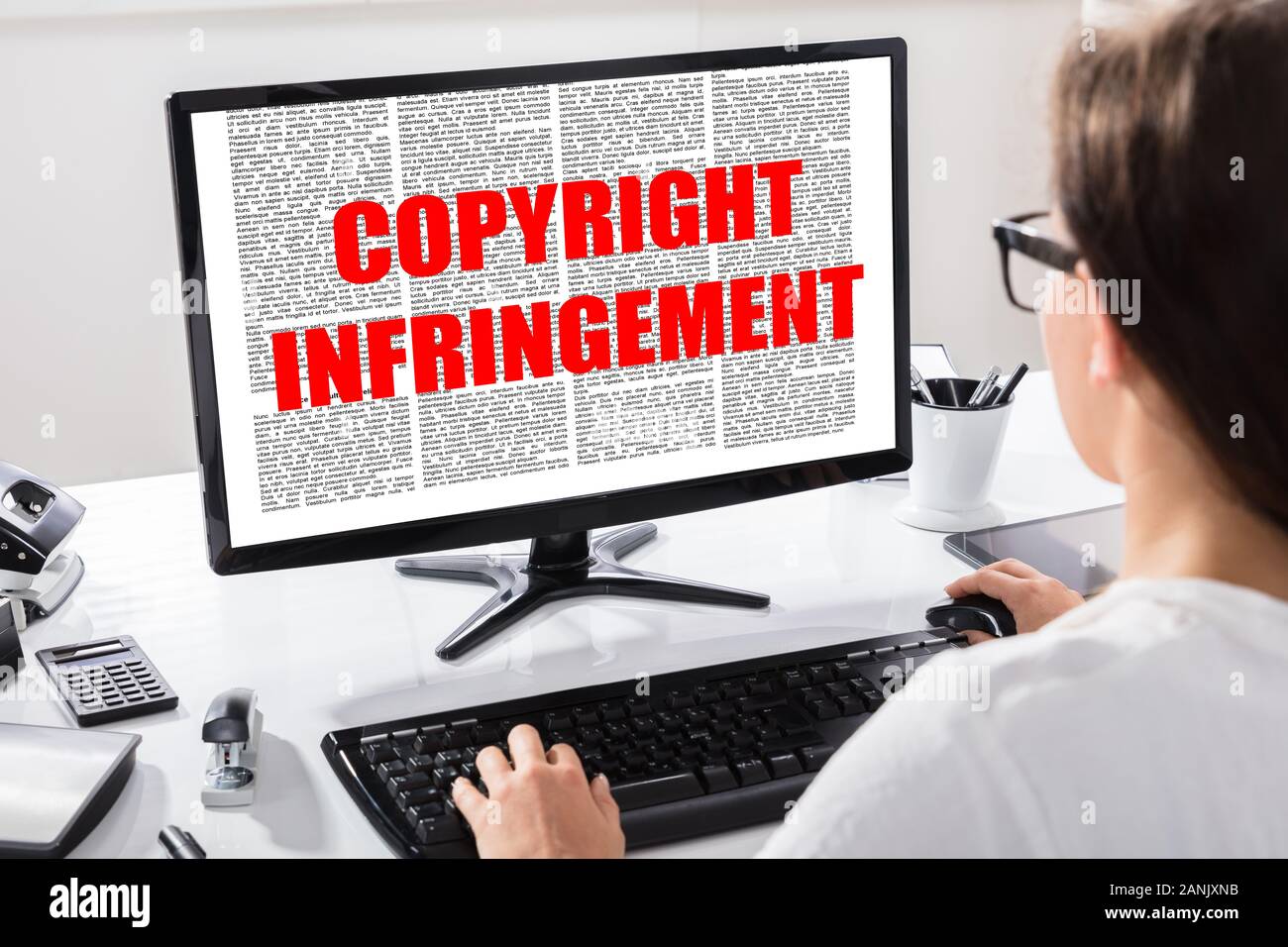 Vista posteriore di una giovane donna la lettura di accordo con la violazione dei diritti di autore del testo su schermo del computer Foto Stock