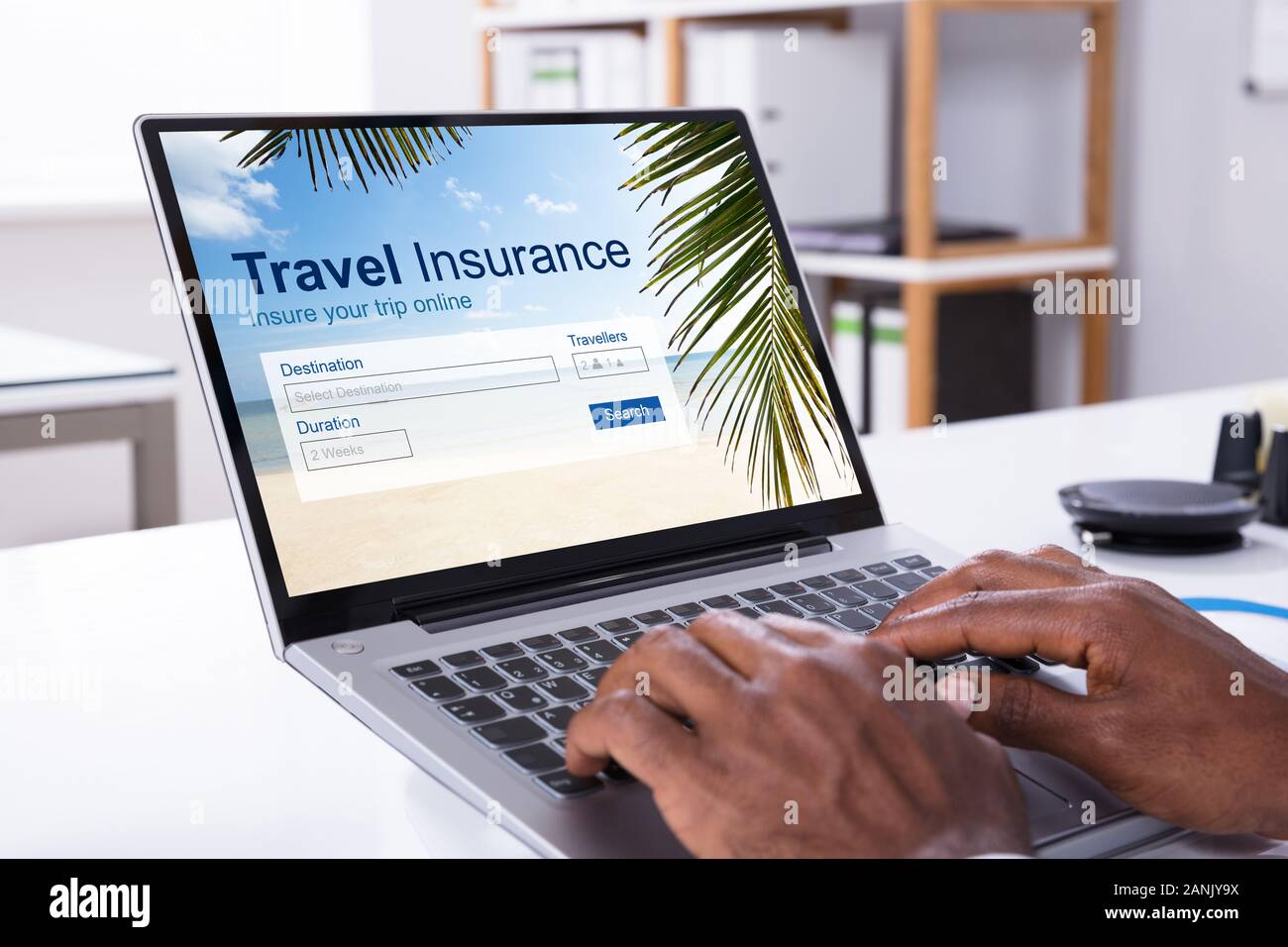 Persona con le mani in mano la digitazione sulla tastiera del laptop con assicurazione di viaggio applicazione sullo schermo in ufficio Foto Stock