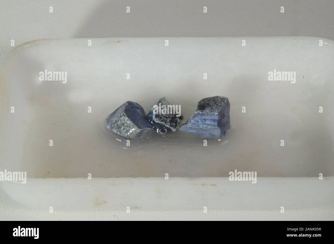 Primo piano su campioni dell'elemento metallico di potassio (K). I campioni devono rimanere coperti di olio per evitare la corrosione, quindi anche un sottile strato di azzurrognolo Foto Stock