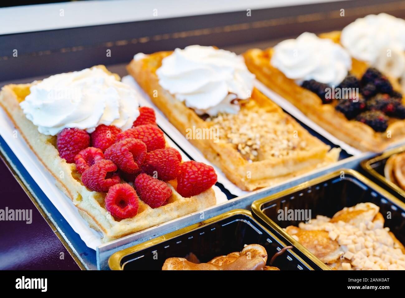 Cialde belghe cibo di strada con diversi condimenti, frutta, Dolci, panna montata. Vetrina pasticceria cialde belghe di vari tipi. Stock Photo Foto Stock