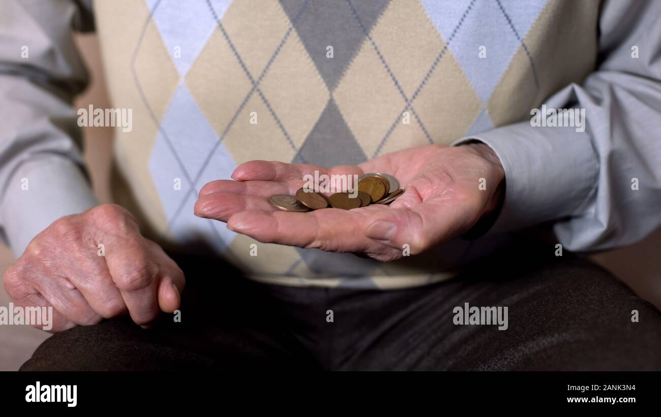 Uomo maturo holding pound centesimi, la vecchiaia la povertà, assicurazione pensionistica, carta di credito Foto Stock