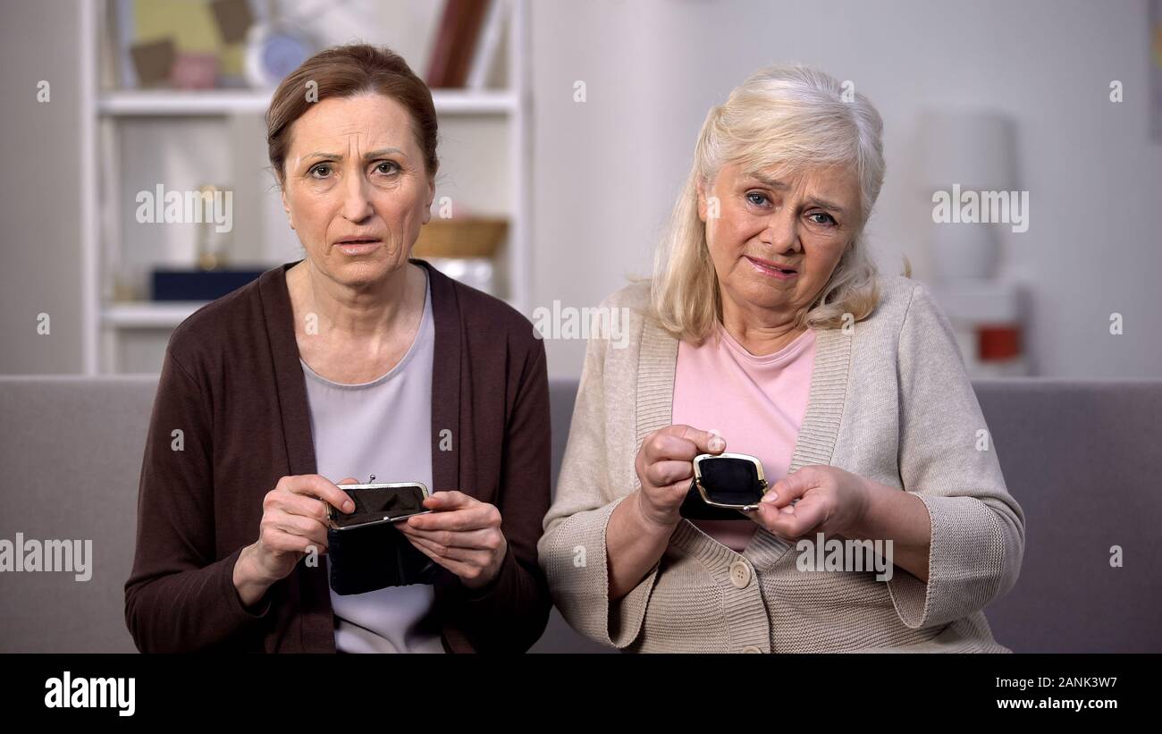 Triste pensionati signore guardando la telecamera che mostra vuoto portafogli, povero budget, basso reddito Foto Stock