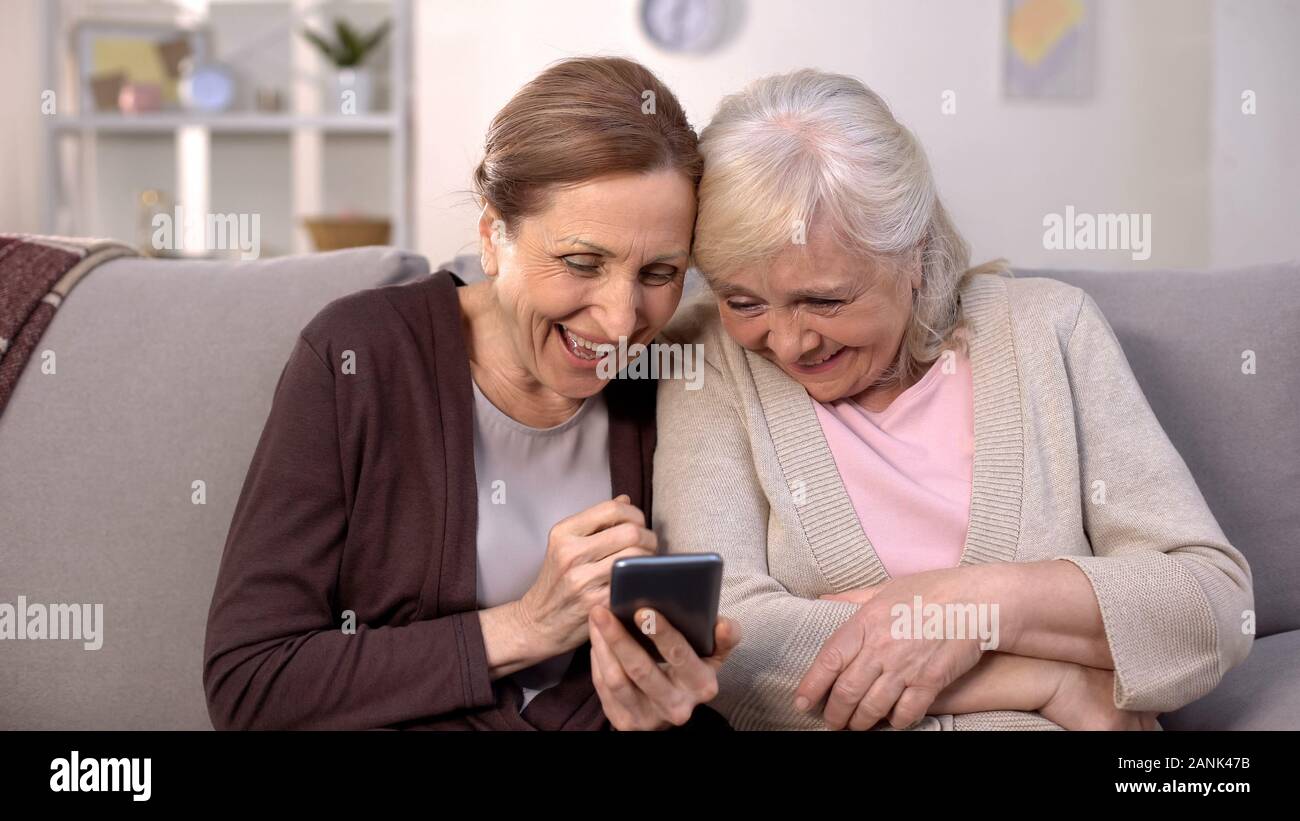 Allegro donne anziane guardando le foto sullo smartphone ridendo, buoni ricordi, divertente Foto Stock