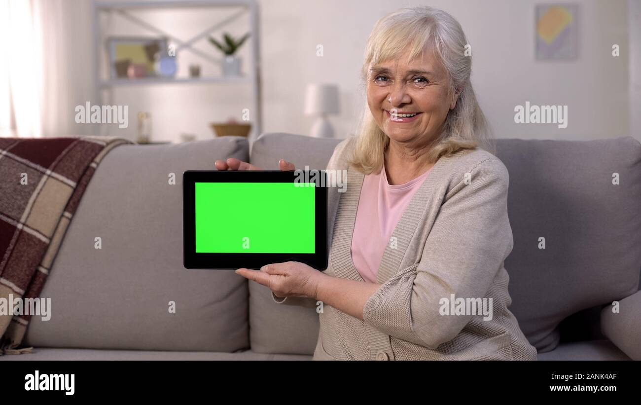 Sorridente coppia lady tenendo premuto lo schermo verde tablet nelle mani, facile servizi bancari e shopping online Foto Stock