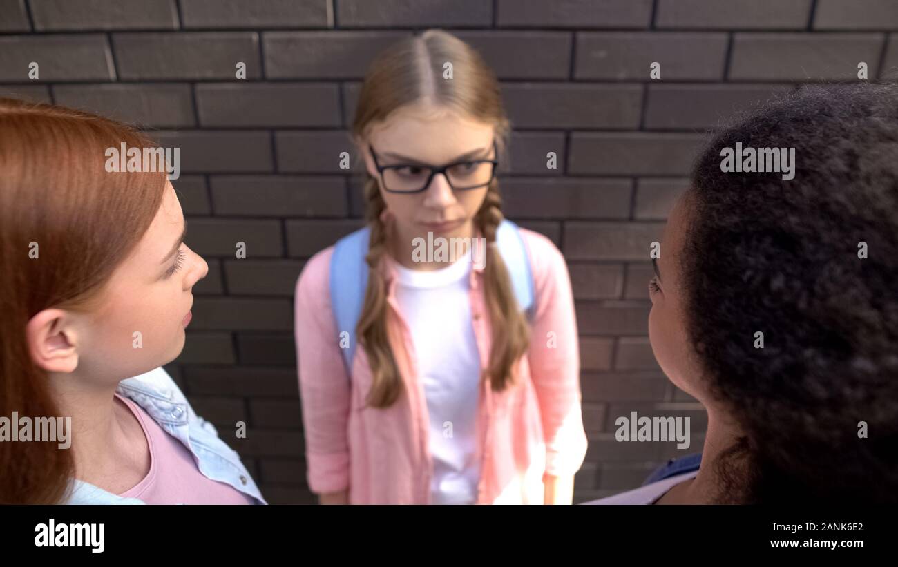 Gli adolescenti guardando il compagno di scuola, beffandosi pupilla femminile, il bullismo crudeltà, abuso Foto Stock