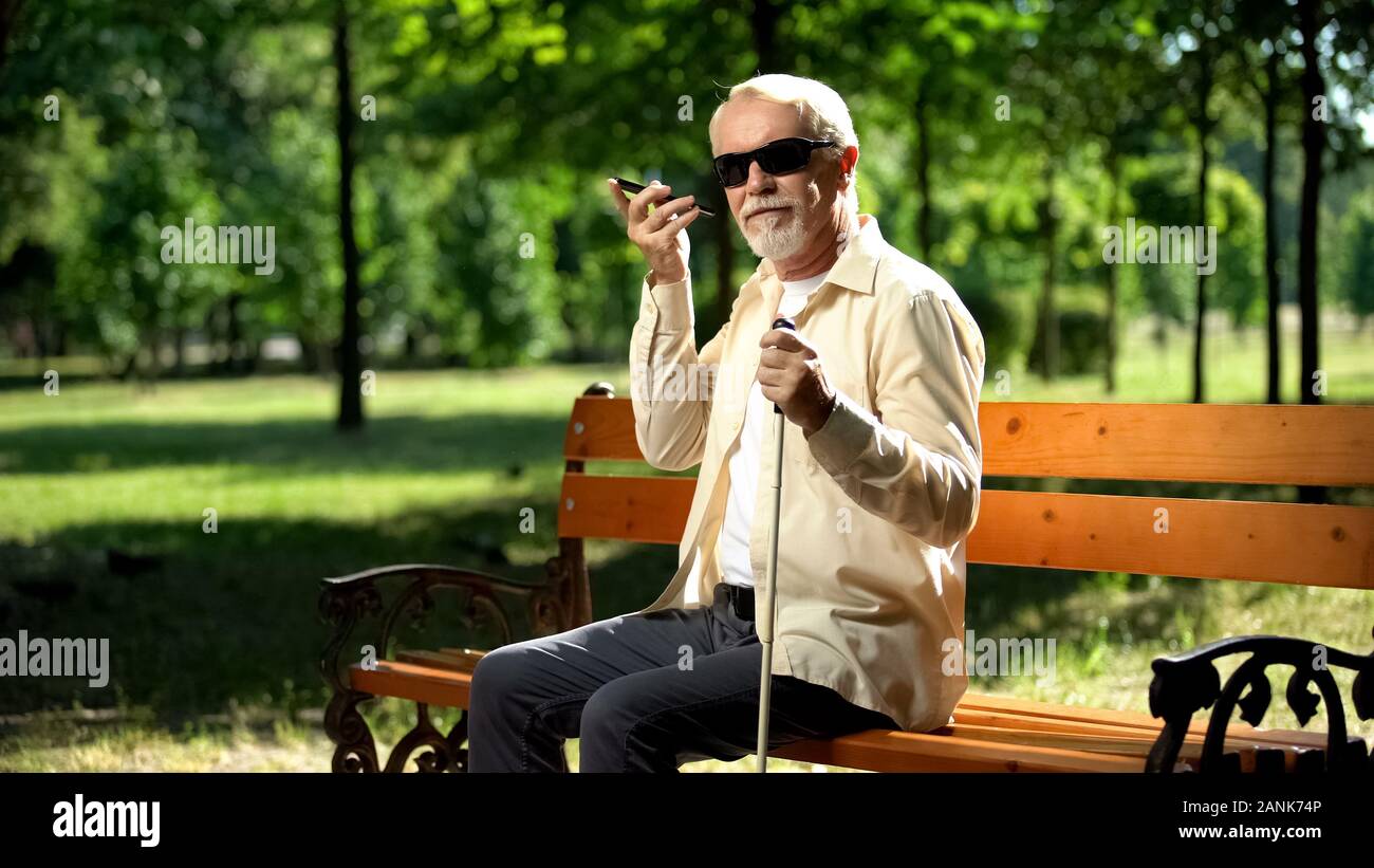 Ipovedenti vecchio uomo utilizzando Controllo vocale app nello smartphone, innovazioni Foto Stock