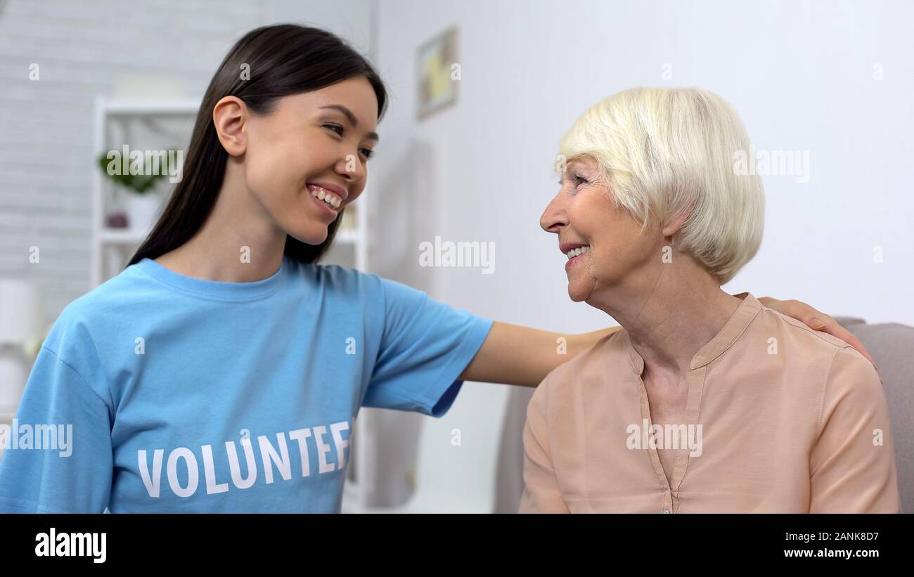 Donna in volontario T-shirt e senior donna guardando ogni altro, caregiving Foto Stock