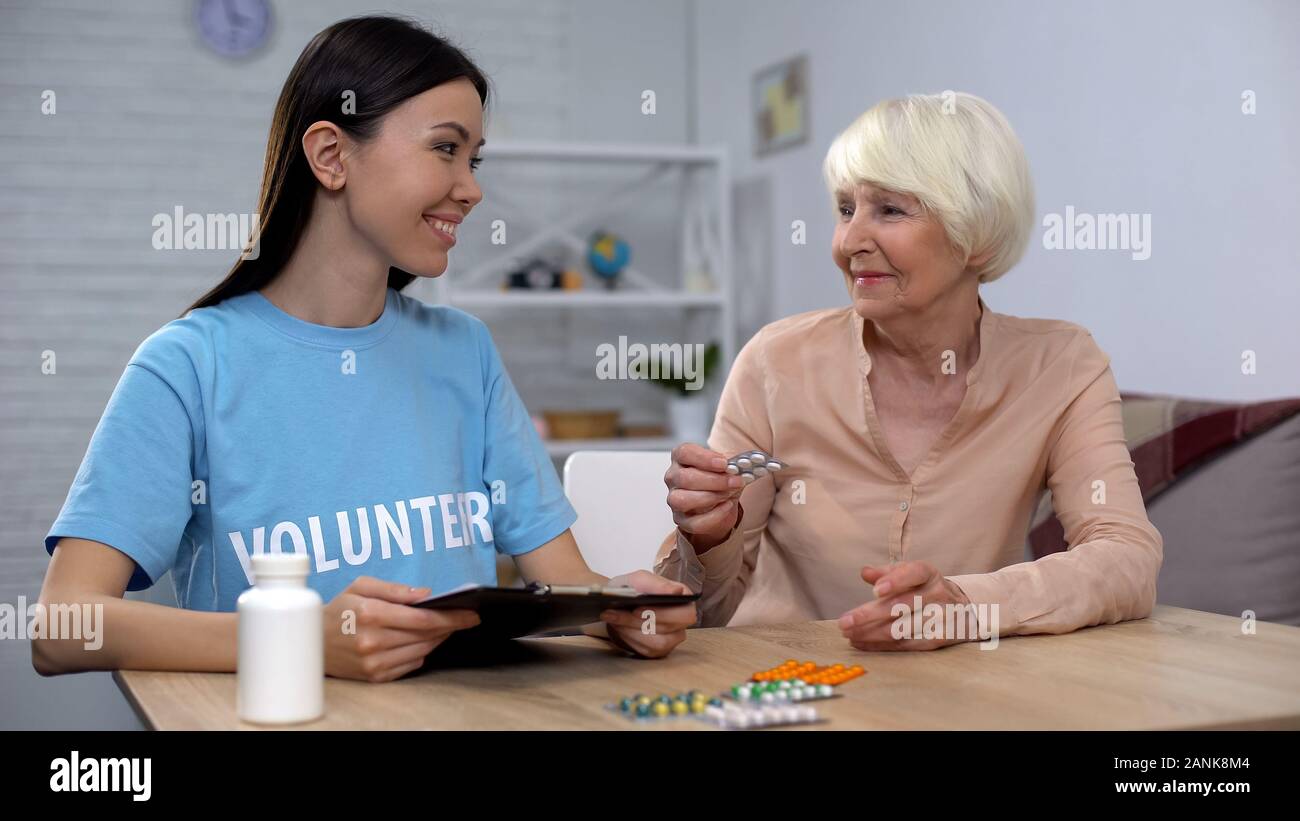 Volontari femmina dando libero farmaci per l'anziana signora, assicurazioni sociali, aiuto Foto Stock