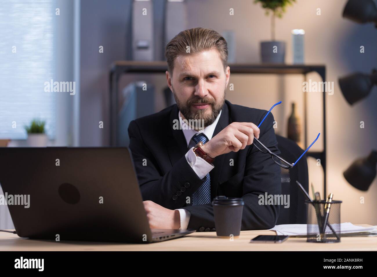 I capelli castani barbuto Ufficio ponendo dipendente da un laptop Foto Stock