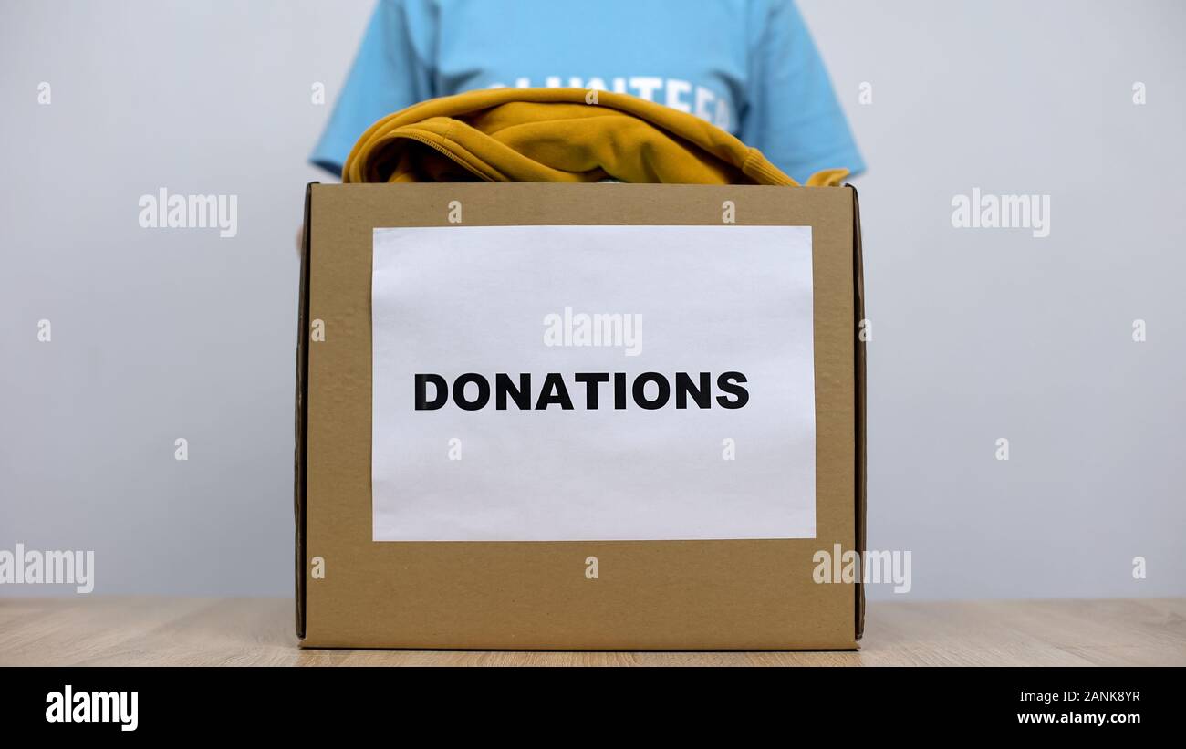 Tipo attivista femmina in piedi dietro donazione box con vestiti, orfanotrofio care Foto Stock