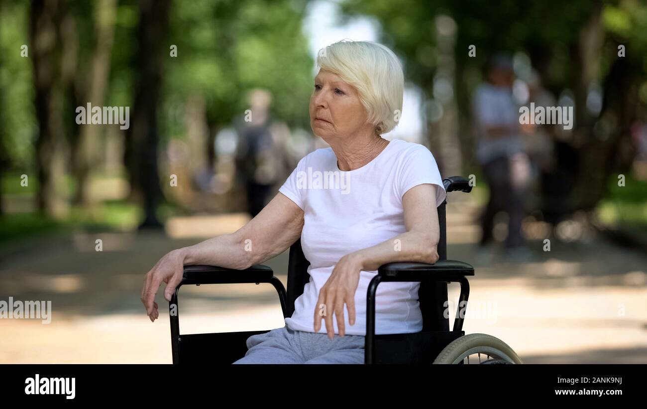 Sconvolto anziani donna seduta in carrozzina presso la casa di cura park, malattia terminale Foto Stock