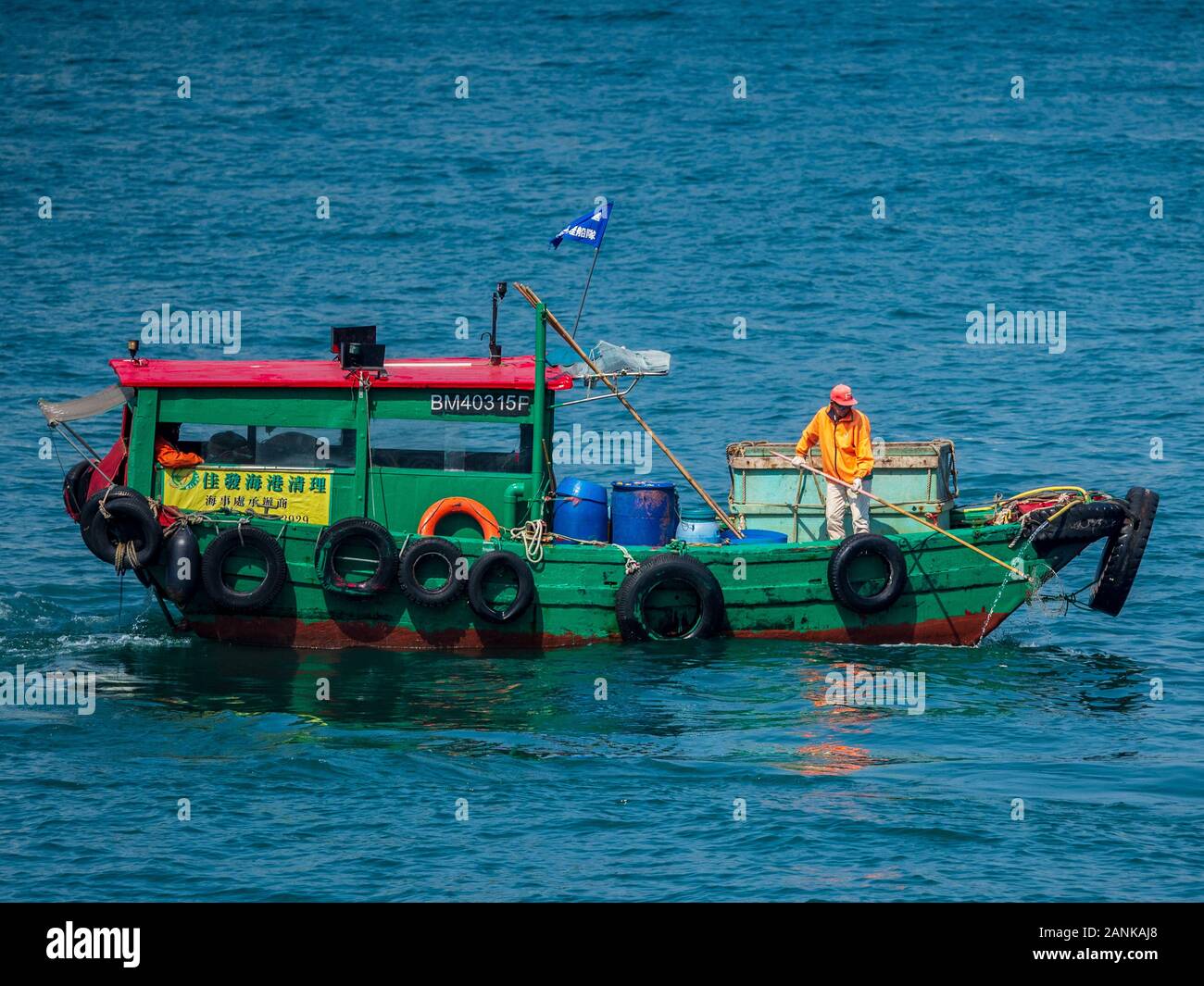 Raccolta Rifiuti Porto Di Hong Kong. Le barche della raccolta dei rifiuti pescano i flotsam e i jetsam di plastica dal porto di Hong Kong, Cina Foto Stock