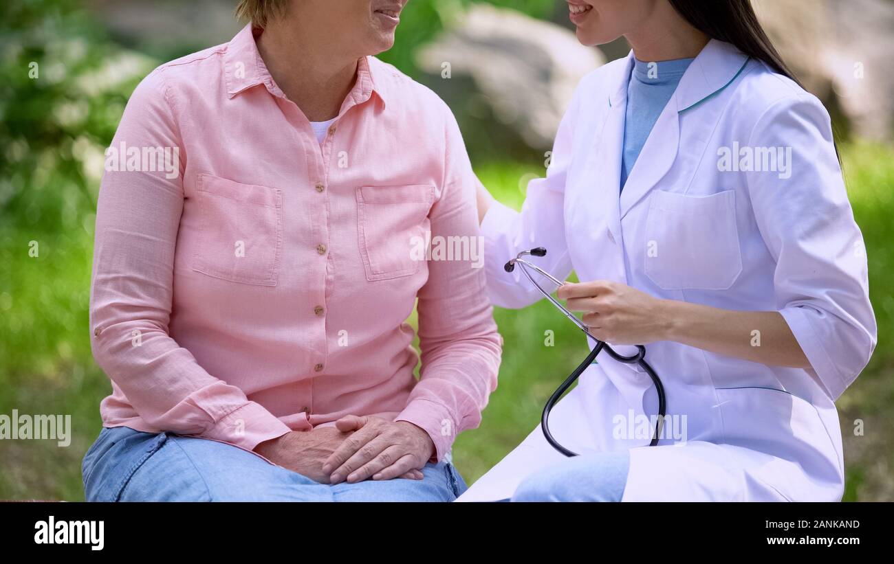 Sorridente lavoratore medico avvolgente di età paziente seduti all'aperto, cure mediche Foto Stock