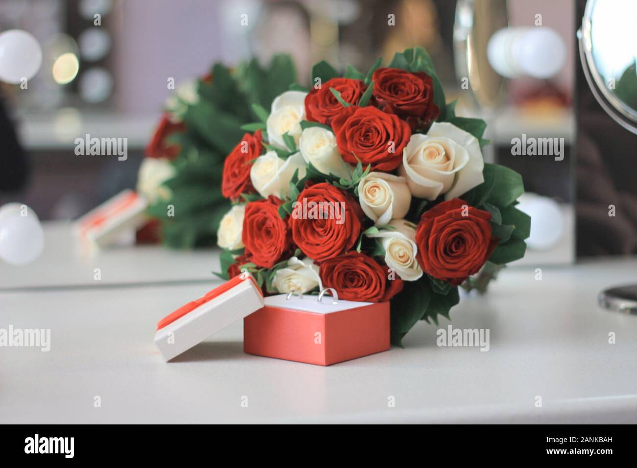 Rose rosse e scatola con anello d'oro. Anello di fidanzamento nella casella di gioielli e fiori su legno rustico sfondo. Il giorno di San Valentino o proposta di matrimonio Foto stock