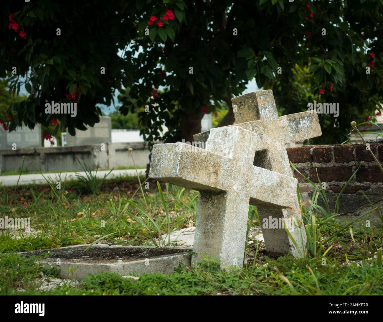 Due vecchi e stagionato lapidi cristiane insieme pendente sul sagrato della Chiesa come segno di amore eterno. Erba circostante tombe sul sagrato, albero leafs Foto Stock