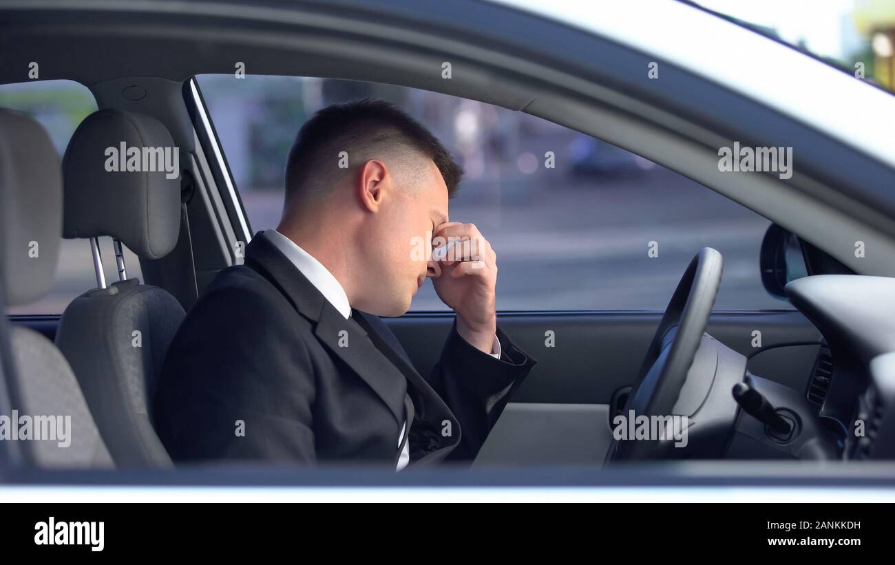 Esaurito maschio in abito formale seduti sul sedile di guida, vita stressante, sovraffaticamento Foto Stock
