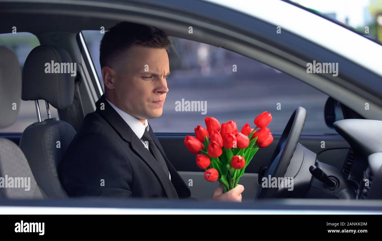 Uomo infelice guardando il mazzo di tulipani e decidendo di auto, rottura Foto Stock