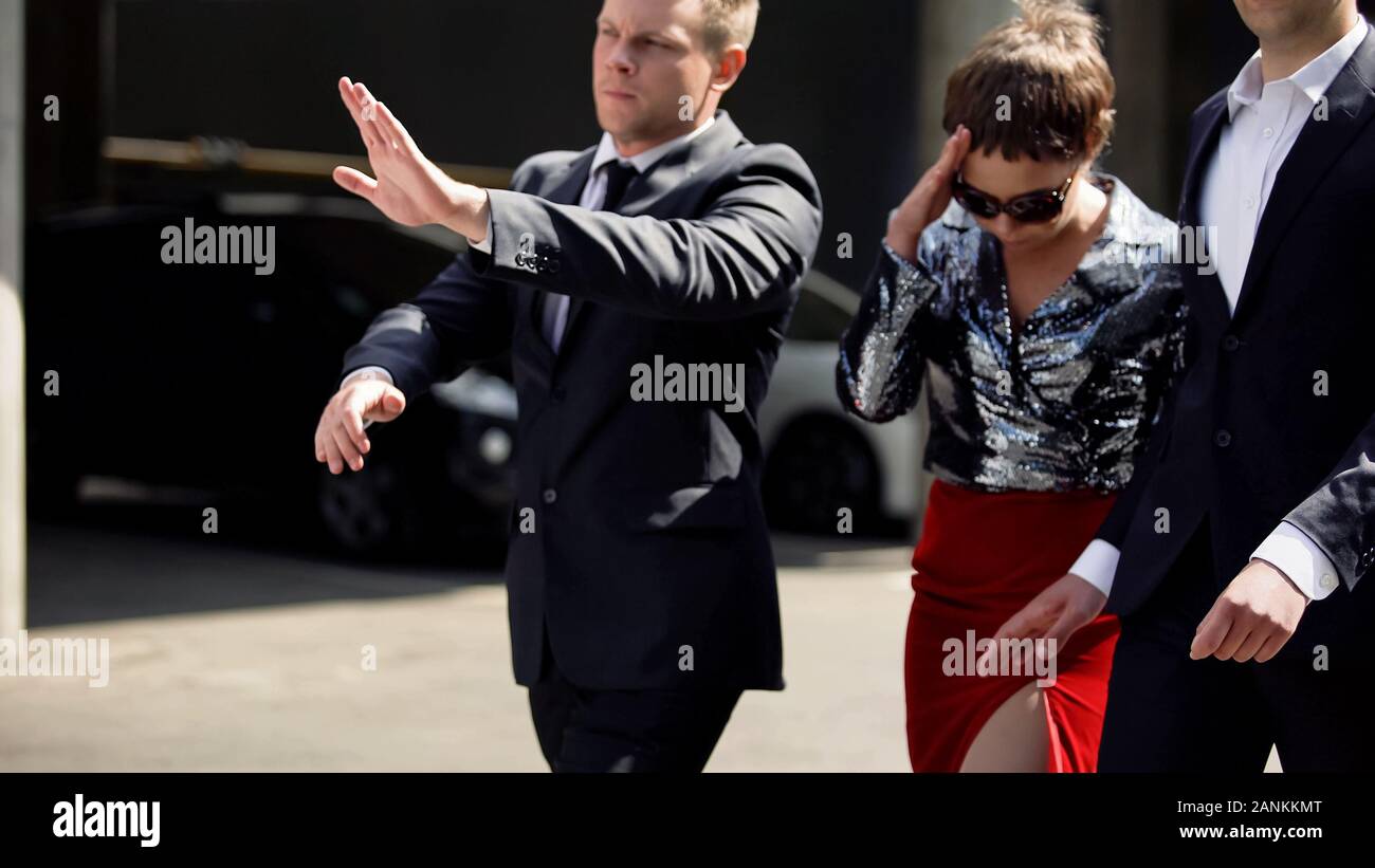 Celebrity guardie del corpo proteggere l'attrice dal fastidioso fotoreporter all'aperto Foto Stock