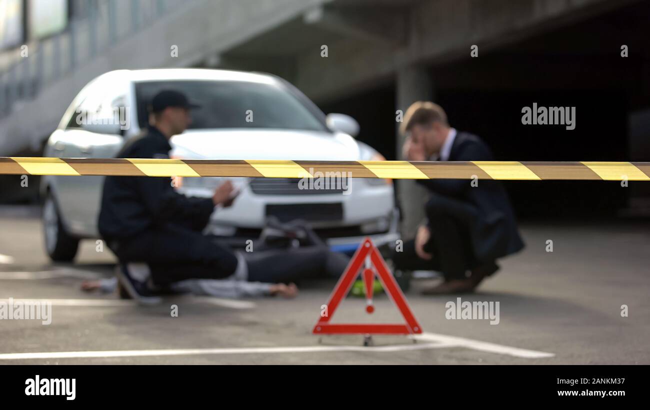 Nastro di segnalazione anteriore del poliziotto e driver in scena dell'incidente, sicurezza su strada Foto Stock