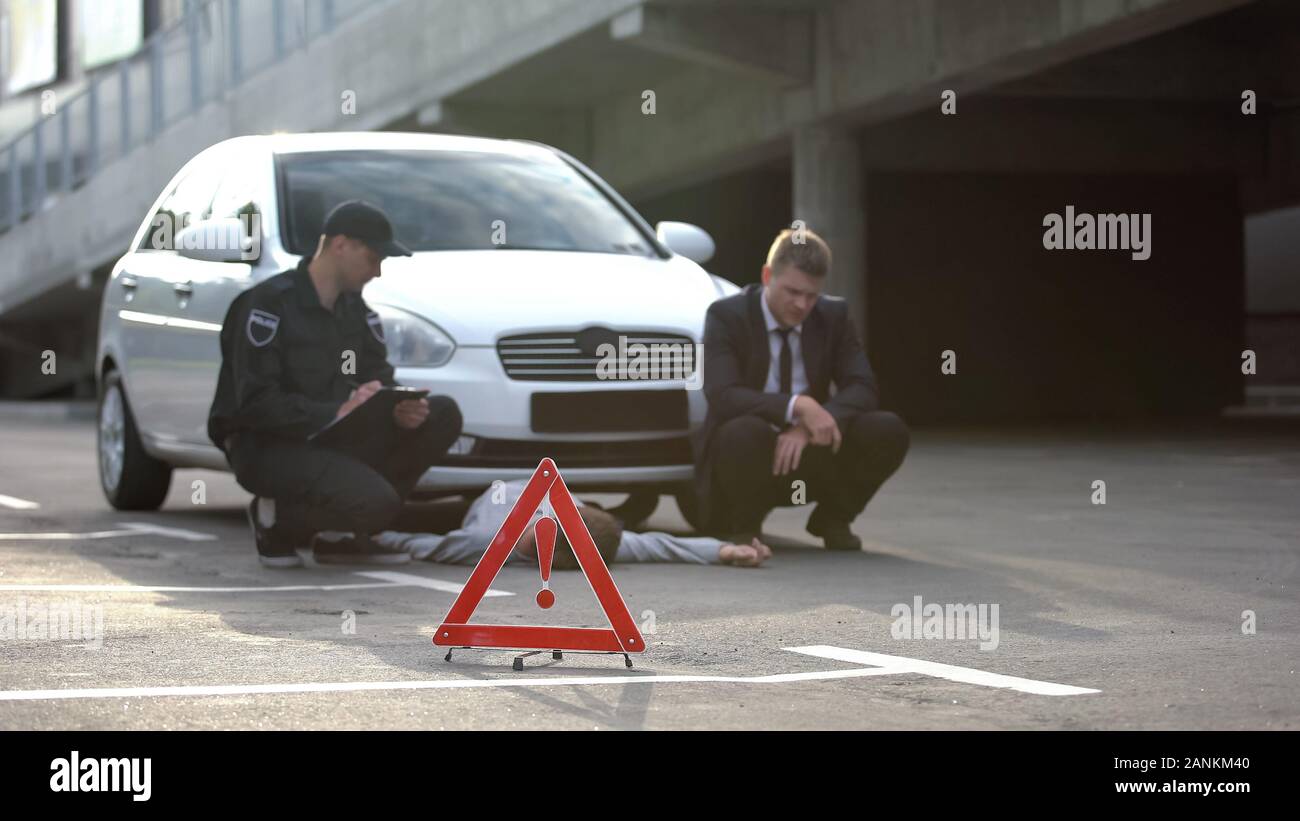 Segno di emergenza su strada, poliziotto con driver maschio la scrittura di report, incidente di automobile Foto Stock