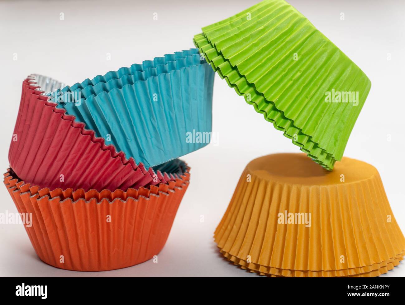 Stretto shot di coloratissimi cupcake wrappers impilati in due pile su sfondo bianco Foto Stock