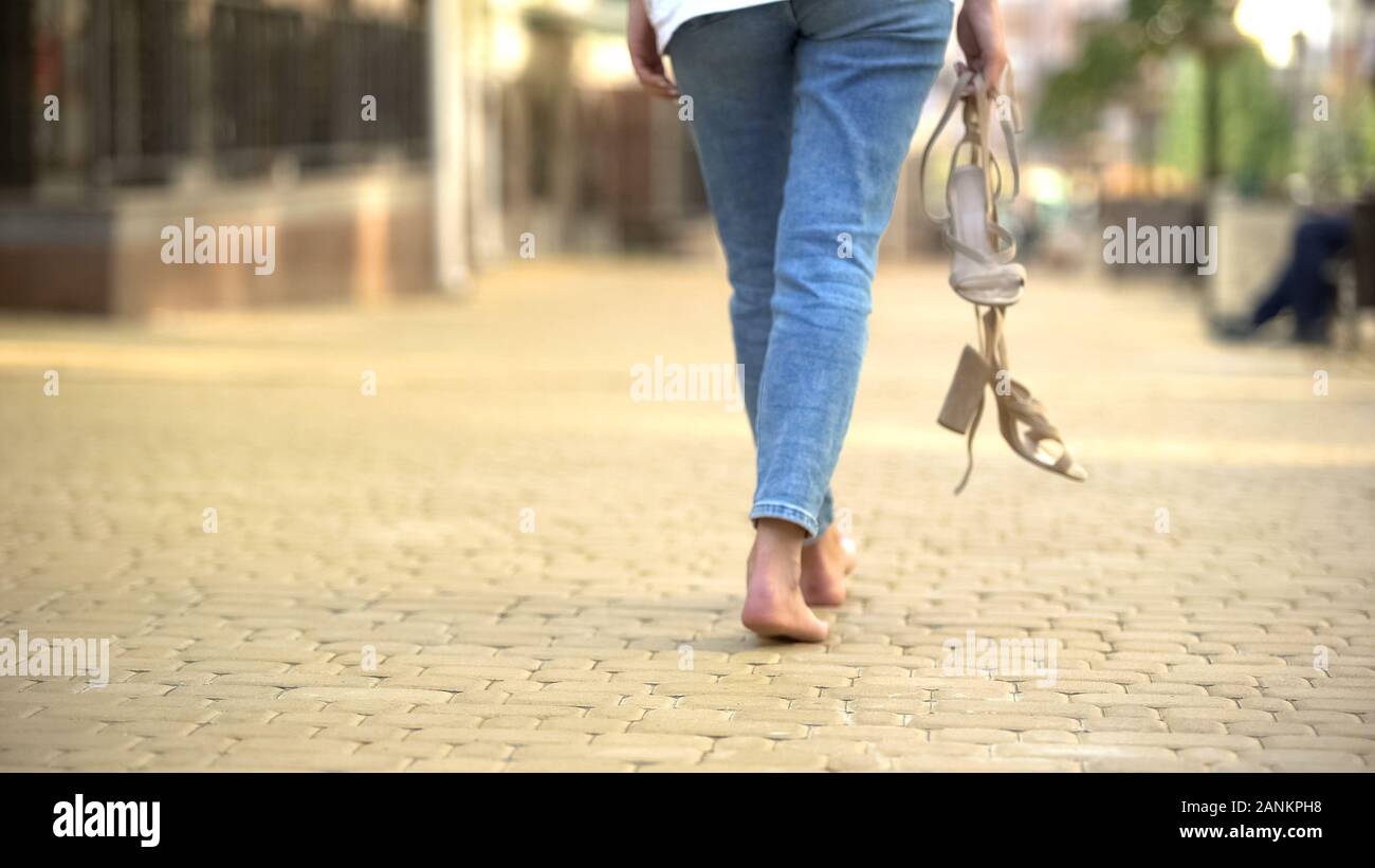A piedi nudi ragazza camminare per strada tenendo in alto le mani-sandali  con tacco, libertà Foto stock - Alamy