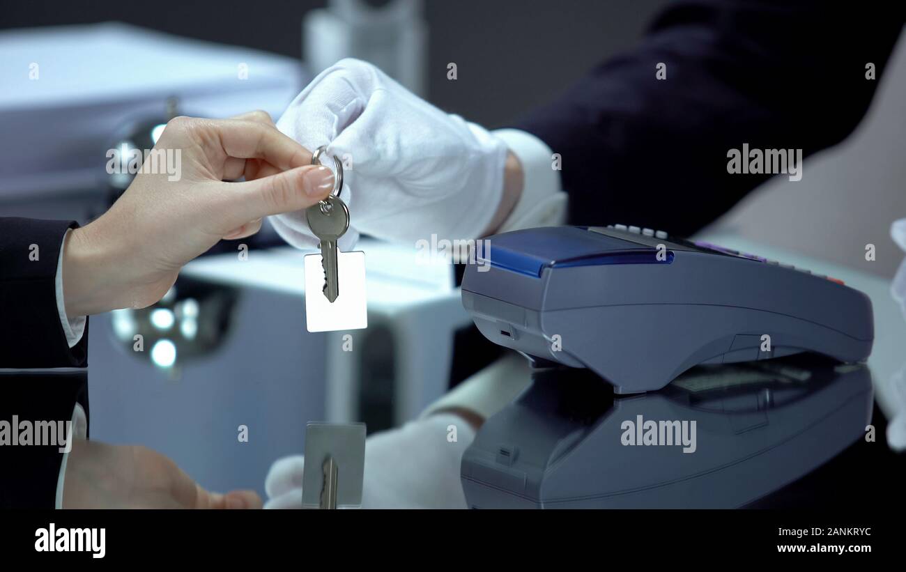 Receptionist dando chiave dalla camera di albergo a femmina dopo il pagamento senza contatto Foto Stock