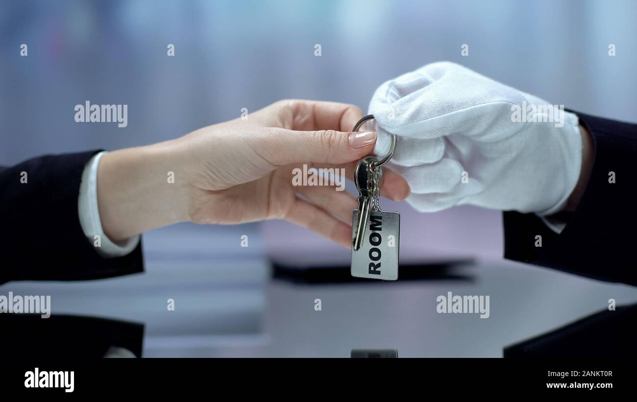 Hotel receptionist dando a mano il cliente chiavi dalla camera prenotata, ospitalità Foto Stock