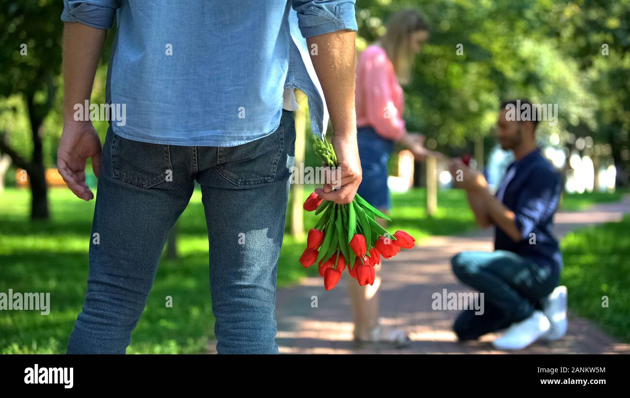Lonely Man con tulipani rossi guardando propone maschio fidanzate, cuore spezzato Foto Stock