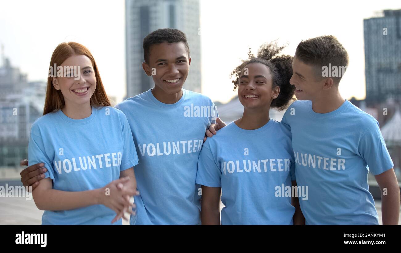 Sorridente teen gruppo volontario in t-shirt guardando la telecamera, aiuto, programma sociale Foto Stock