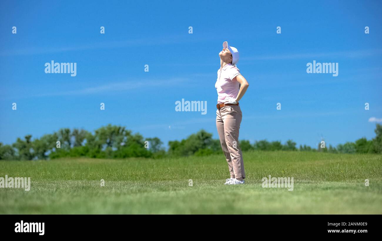 Donna inesperti golfista insoddisfatti per fallito colpo, guardando in alto, perdente Foto Stock