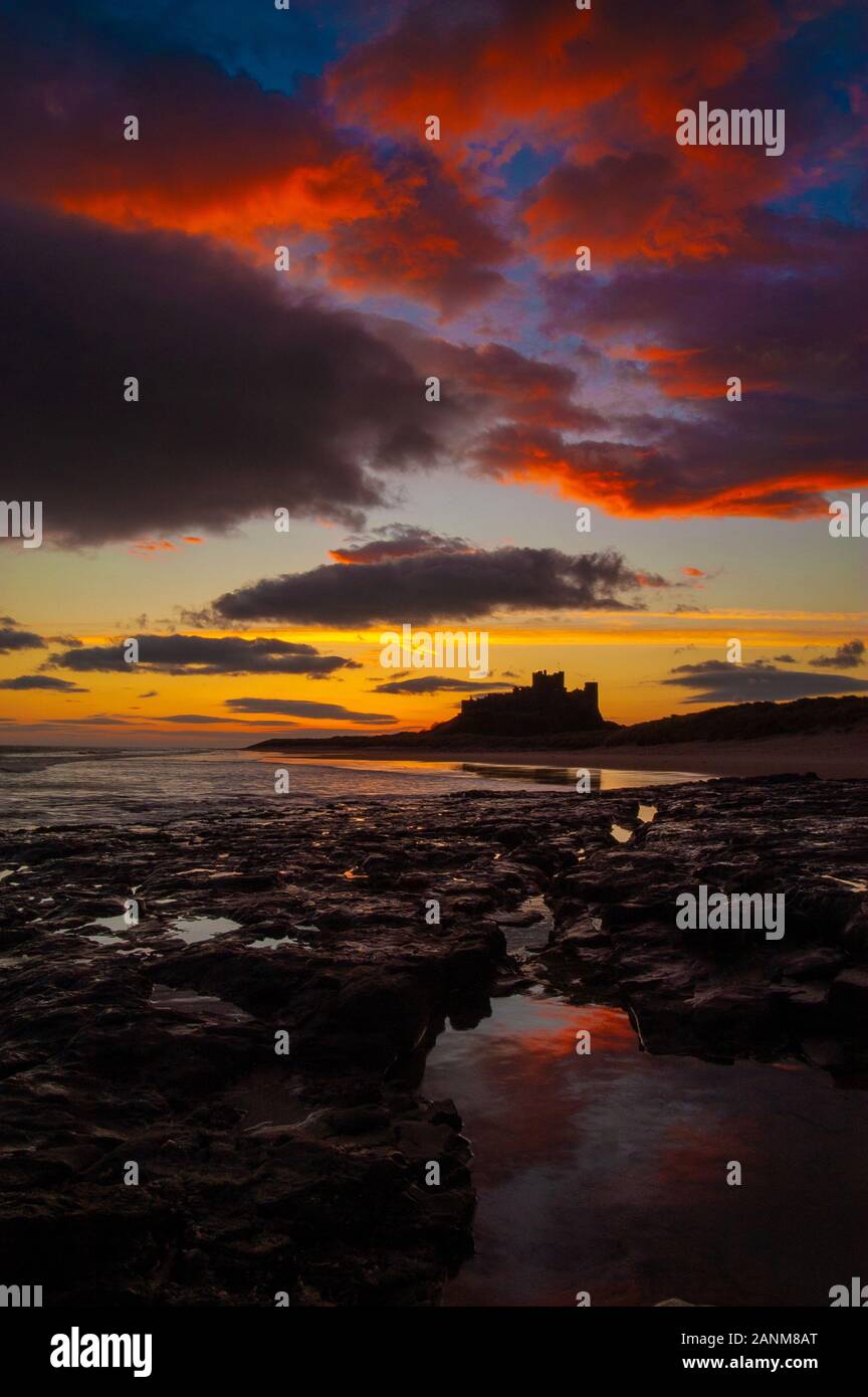 Inverno alba sopra il castello di Bamburgh uno dei più iconica stupende viste sul castello nel Regno Unito arroccato su uno sperone di origine vulcanica sulla costa di Northumberland Foto Stock