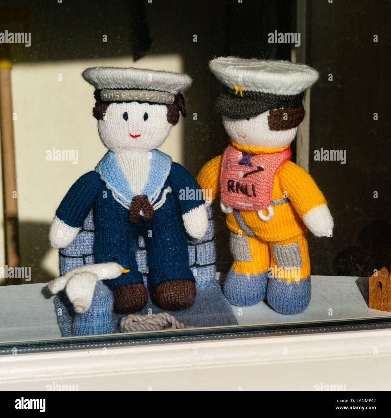 Piccoli fatti a mano a maglia marinaio e RNLI lifeboatman bambole in loro uniformi sul display sul davanzale, St. Ives, Cornwall, Regno Unito Foto Stock