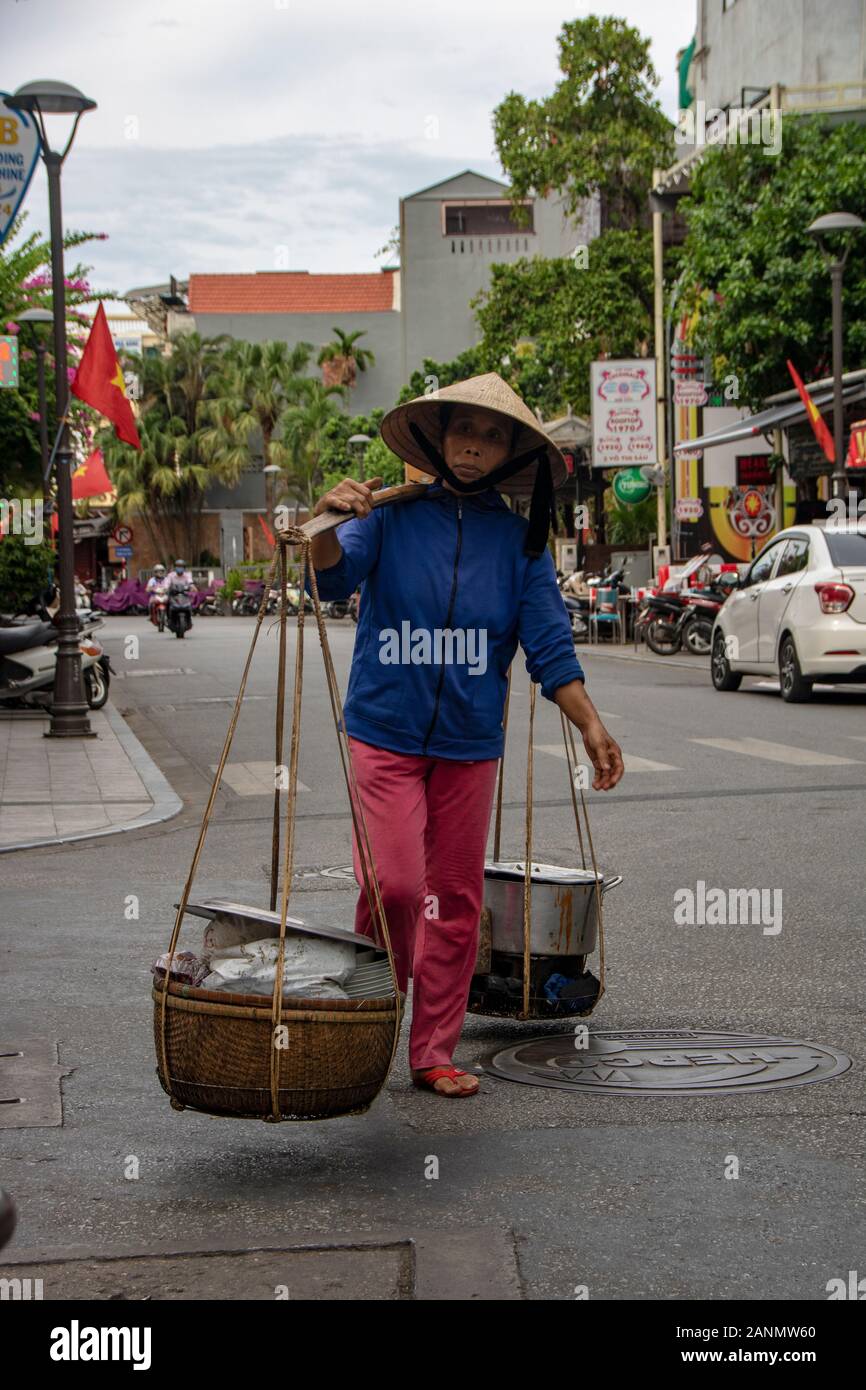 A Hue - Vietnam - agosto 2019 - donna che trasportano merci sulla sua spalla Foto Stock