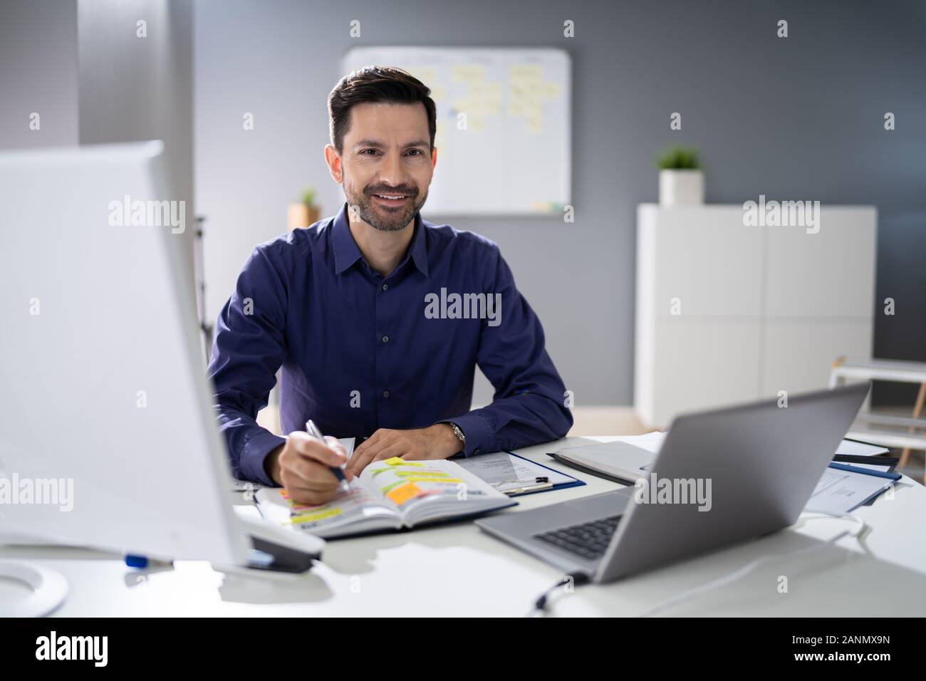 Close-up di un imprenditore il la scrittura a mano nota con la penna nel diario su scrivania Foto Stock