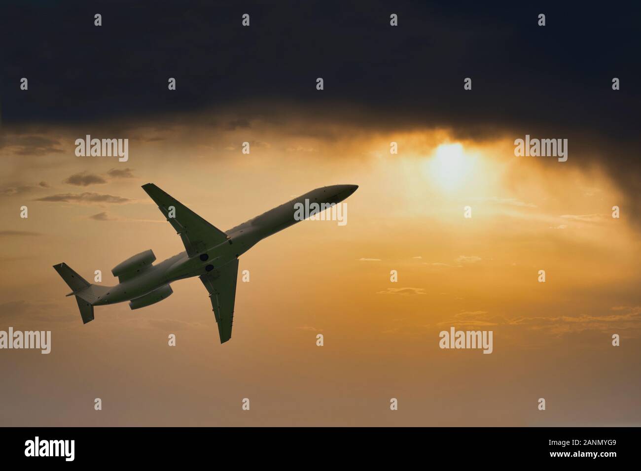 Aeroplano vola alto in Dark nuvole e sole luminoso durante il tramonto Foto Stock