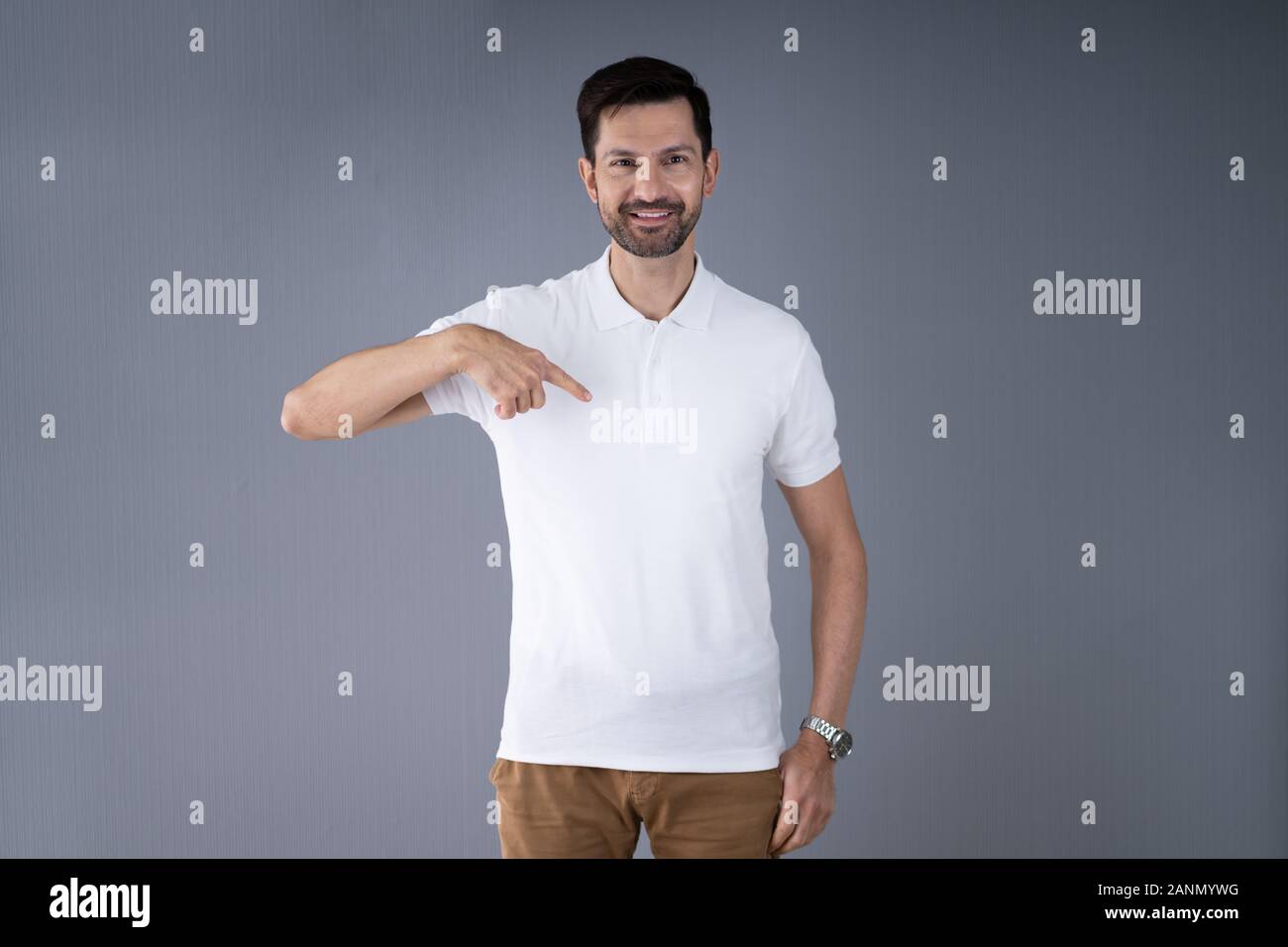 Uomo sorridente in Casuals puntamento permanente a T-Shirt Foto Stock