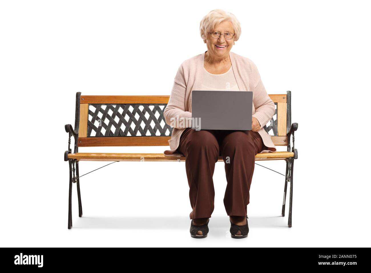 Senior donna con un laptop seduto su una panchina e guardando la telecamera isolata su sfondo bianco Foto Stock