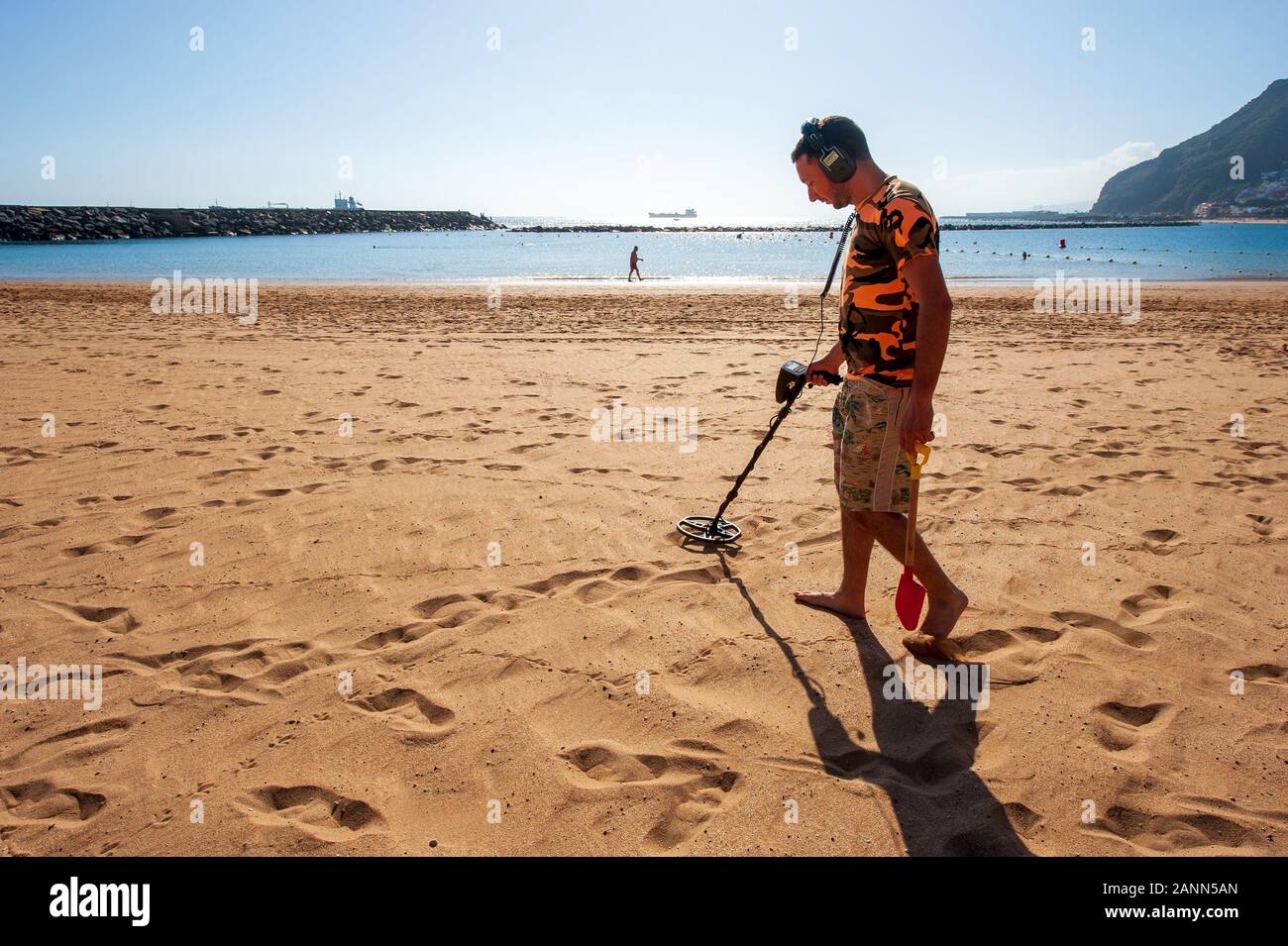 Isola Canarie TENERIFE, Spagna - 23 Dic, 2019: un uomo con un rivelatore di metalli alla ricerca di cose di metallo nella sabbia della Playa de Las Teresitas a Tenerife Foto Stock