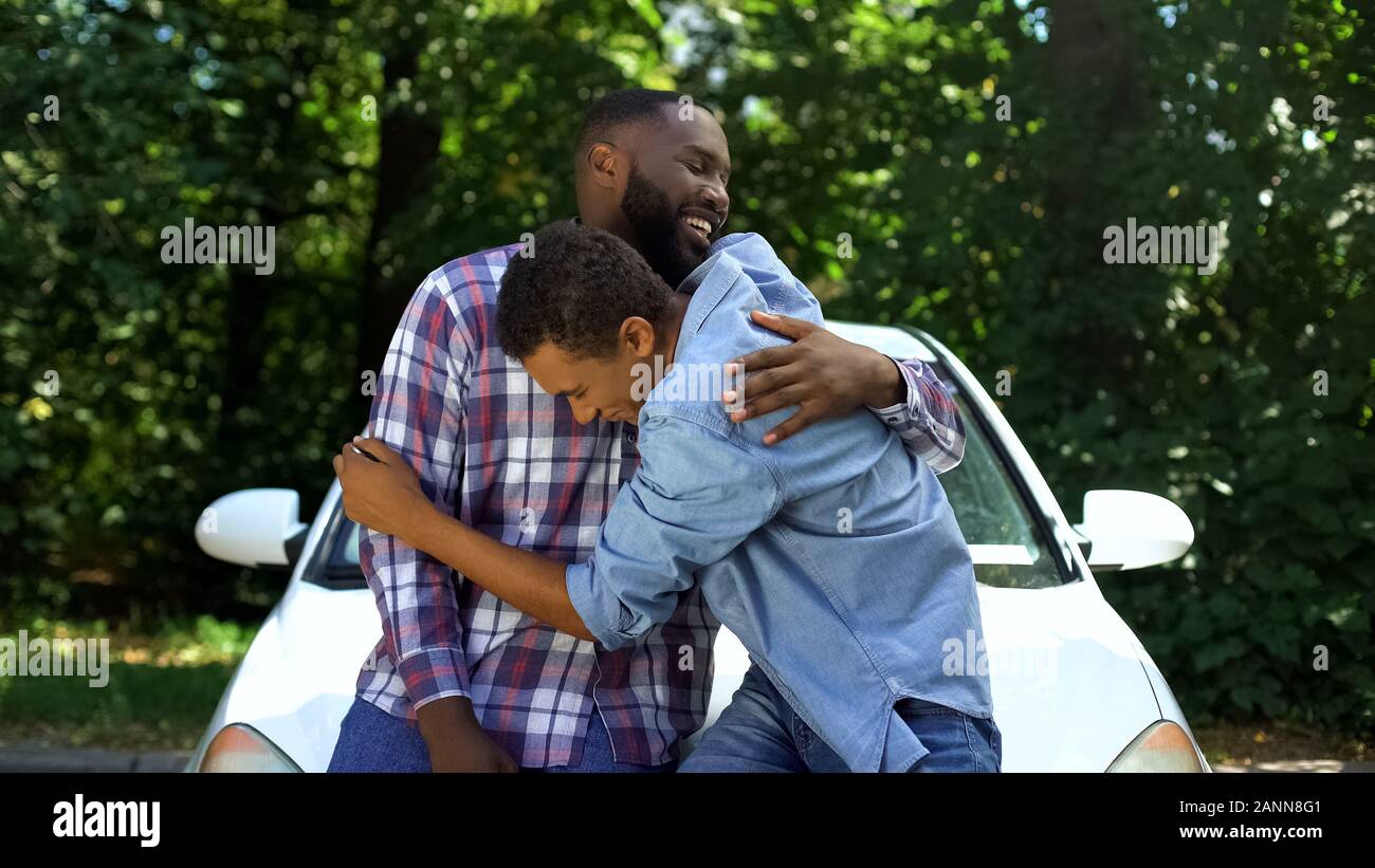 Padre amorevole presentando automobile chiave per il figlio adolescente Felice costeggiata genitore Foto Stock