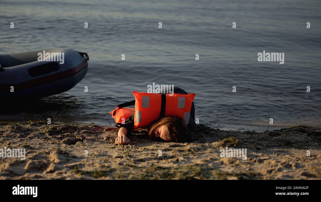 La donna nella vita giacca giacente a terra vicino a barca, vittima del naufragio, incidente Foto Stock