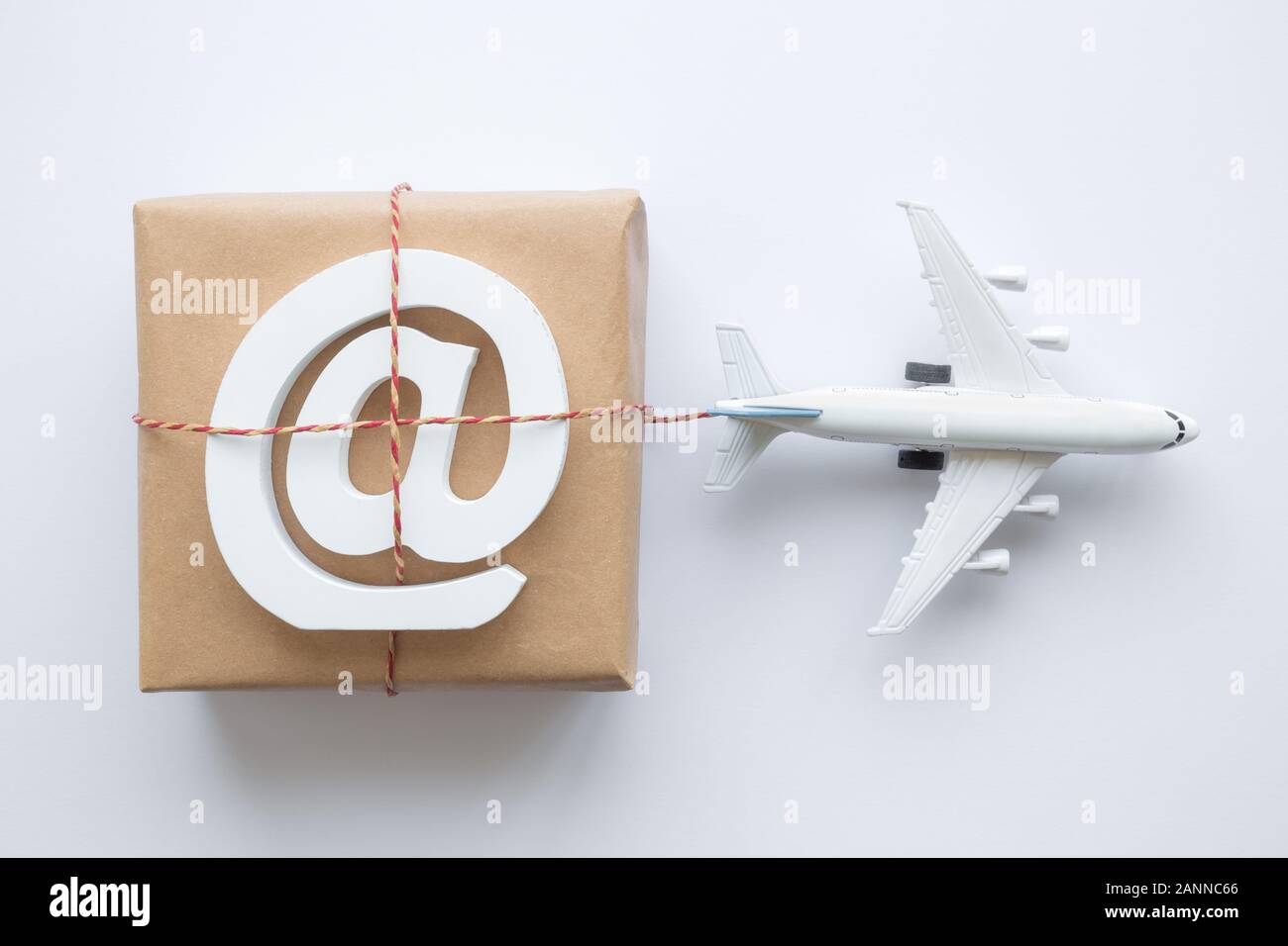 Piatto di laici confezione con l'e-mail simbolo e modello di aeroplano su sfondo bianco. La logistica di spedizione minimo di trasporto concetto creativo. Foto Stock