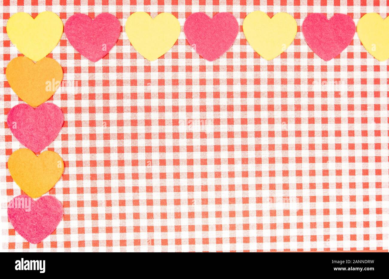Con uno sfondo rosso e bianco tessuto Vichy per il giorno di San Valentino con rosa, giallo e arancione cuori. Il giorno di San Valentino del concetto. Foto Stock