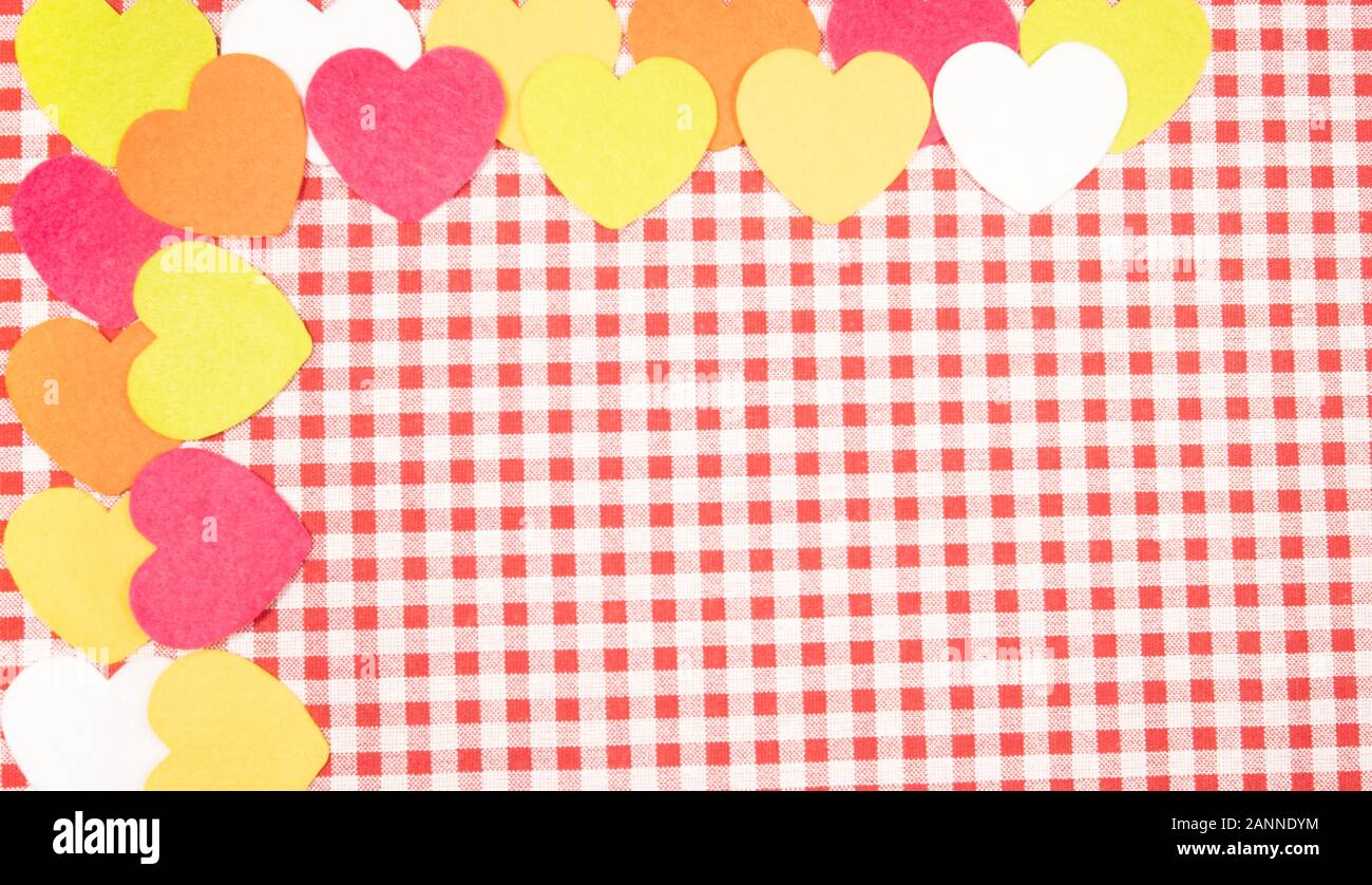 Con uno sfondo rosso e bianco tessuto Vichy per il giorno di San Valentino con rosa, arancione, giallo e bianco cuori. Il giorno di San Valentino del concetto. Foto Stock