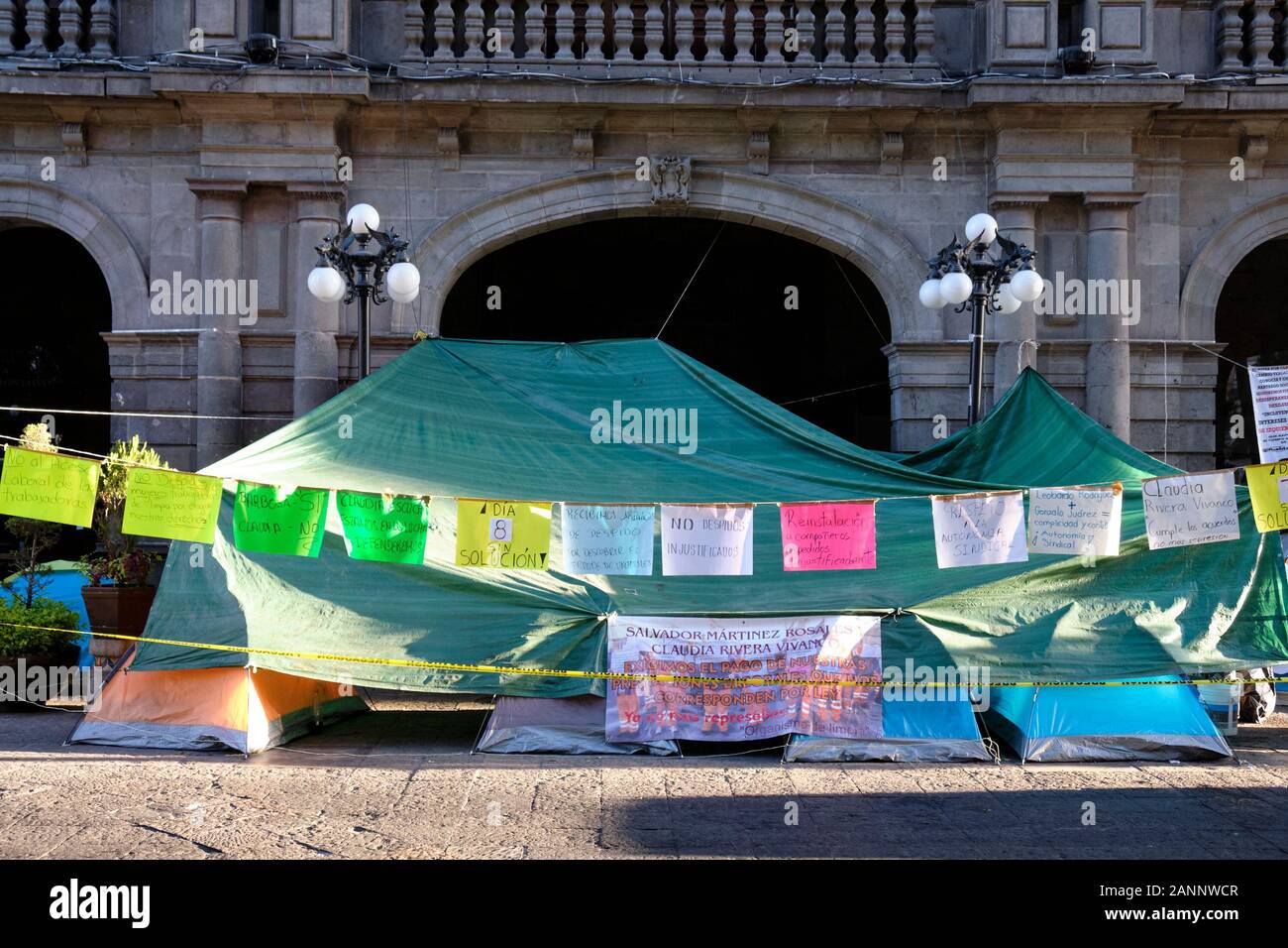 Camping tenda istituito per protestare contro il licenziamento di street cleaners (arance) di fronte al palazzo del municipio. Puebla, Messico. Gennaio 14, 2020. Foto Stock