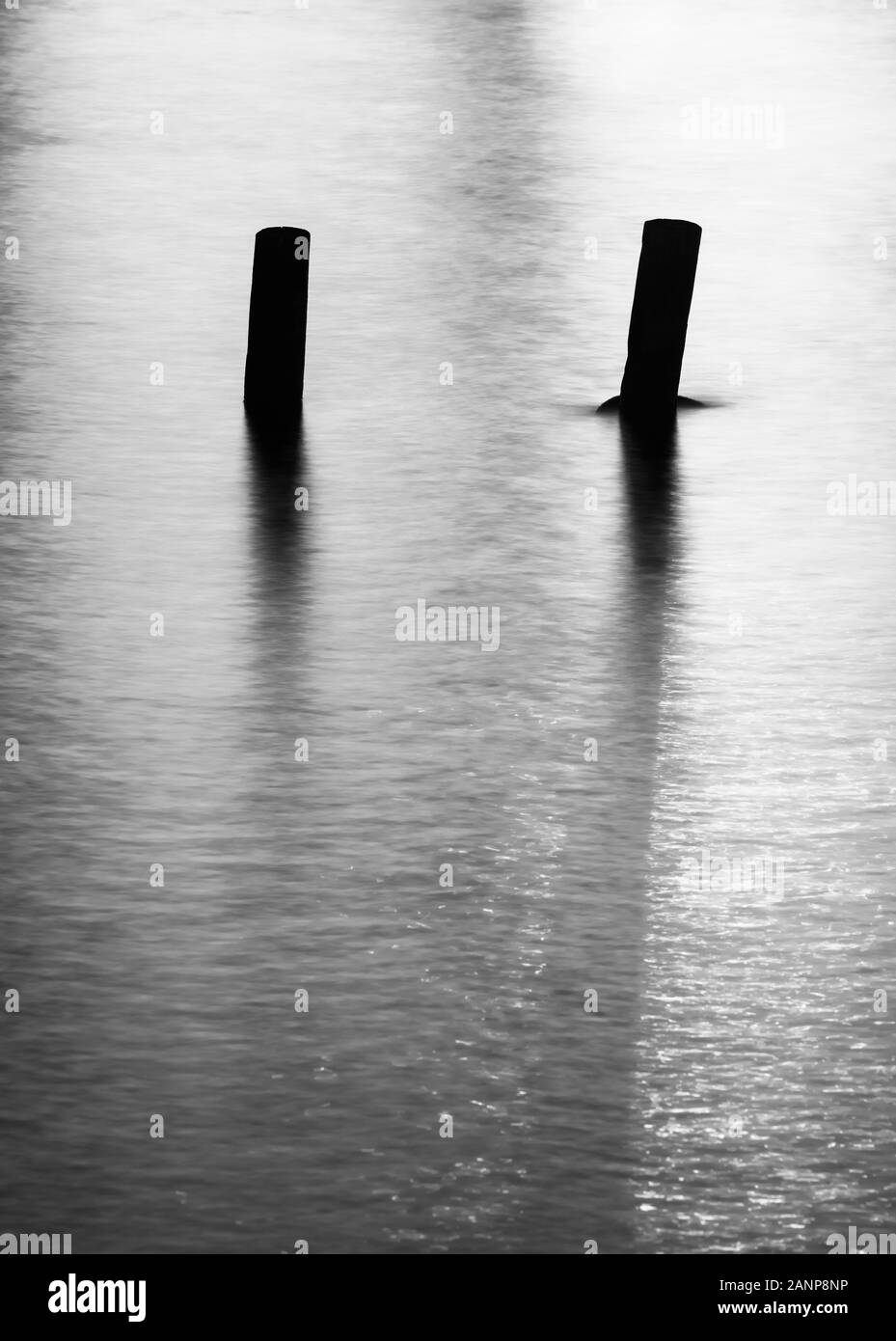 Foto minimalista di pier e tralicci e acqua vicino al tramonto, realizzata utilizzando una lunga esposizione Foto Stock