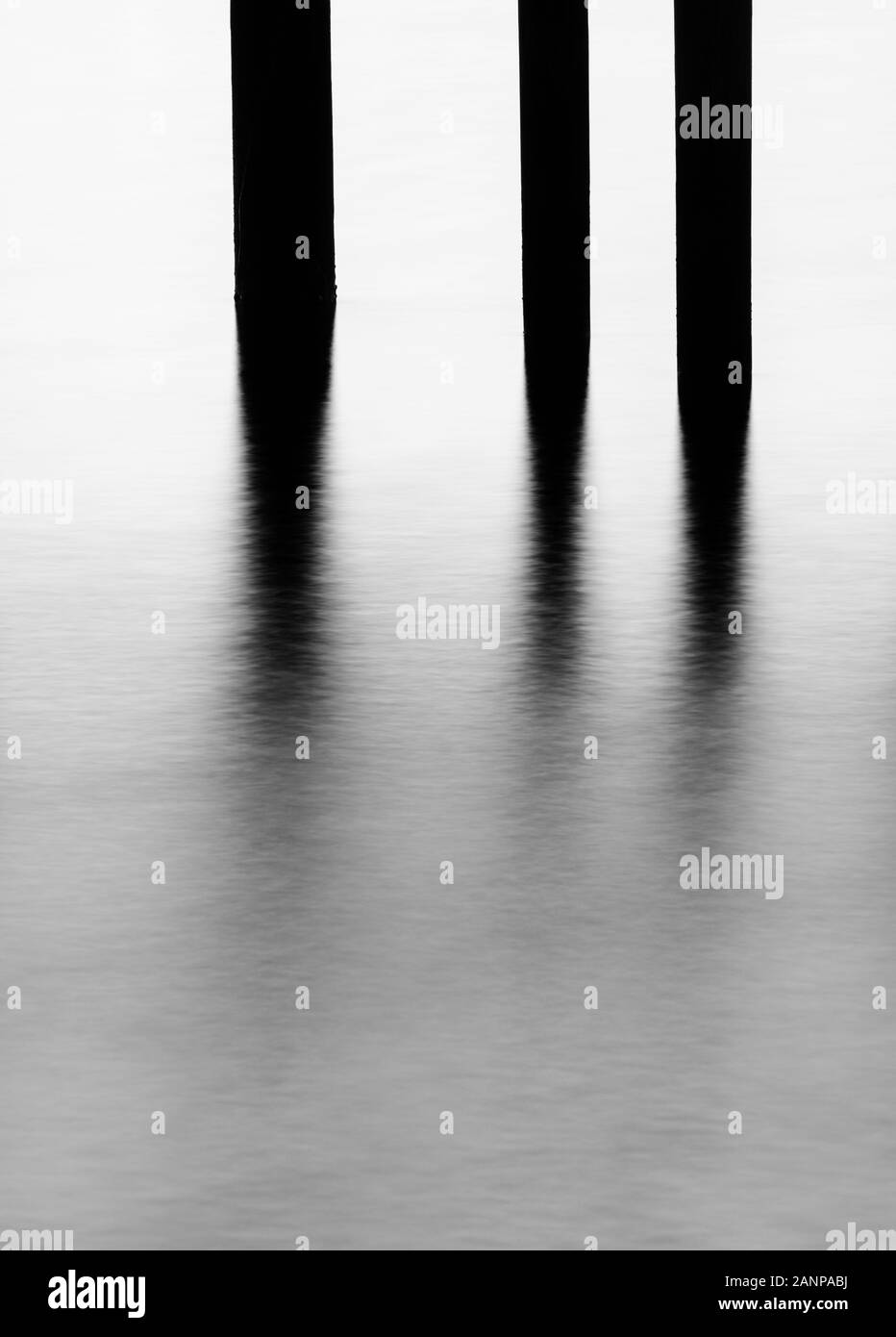 Foto minimalista di pier e tralicci e acqua vicino al tramonto, realizzata utilizzando una lunga esposizione Foto Stock